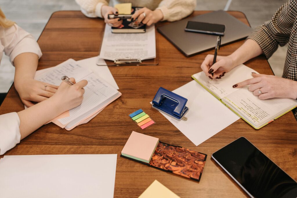 Three colleagues engaged in a collaborative meeting taking notes and reviewing documents.